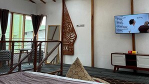 Habitación de hotel con cama, televisor, escalera y vista al exterior.