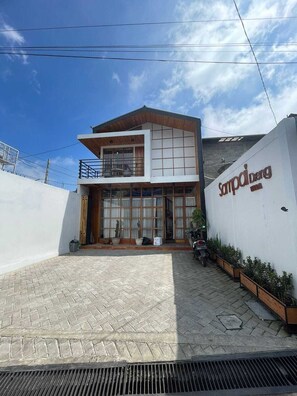 A modern two-story building with a flat roof, large windows, and a sign that reads 'Sampai Berg.' - Villa Sampai Dieng (Dieng Kulon)