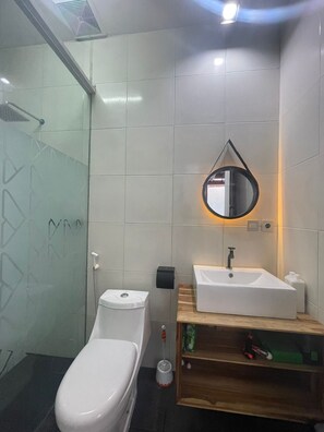 Un baño moderno con inodoro, lavamanos y espejo.