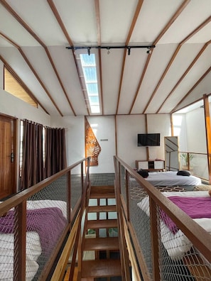 A room with bunk beds, a TV, a staircase, and a window. - Villa Sampai Dieng (Dieng Kulon)