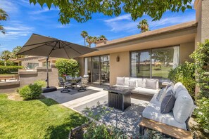 A patio with outdoor furniture, a dining table, and a large umbrella. - *Palm Valley CC, 76643 Daffodil Dr (Palm Desert)