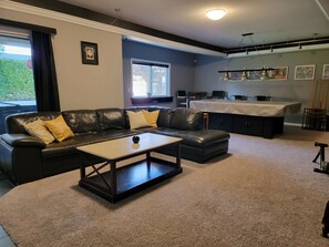 Un salon avec un canapé en cuir noir, une table basse et un coin repas comprenant une table et des chaises.