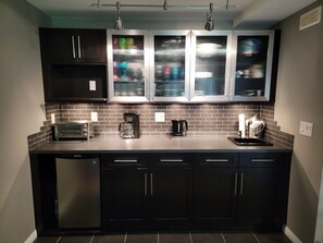 A kitchen with dark cabinets, a toaster, a coffee maker, and a sink.