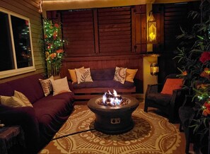 A cozy living room with a central fire pit, a sofa, and a chair.