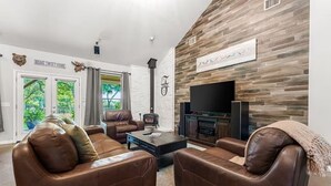 Ein Wohnzimmer mit Ledersofas, einem Kamin, einem Flachbildfernseher und einer Steinwand.