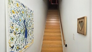 Ein Flur mit einer Holztreppe, einem großen abstrakten Gemälde links und einem herzförmigen Bild rechts.