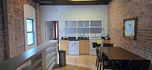 A kitchen with a brick wall, a window, a sink, a stove, and a dining table.