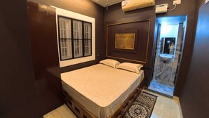 A bedroom with a bed, a window, a mirror, and a bathroom with a sink. - Thulasi My Village My Resort (Papireddipatti)