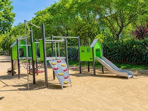 Ein Spielplatz mit Rutsche, Klettergerüsten und Sandkasten.
