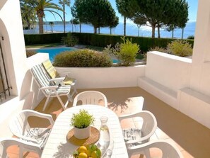 A patio with a table, chairs, a potted plant, and a view of the sea. - Suitur Dorado Onintza beachfront apartment with swimming pool (Cambrils)