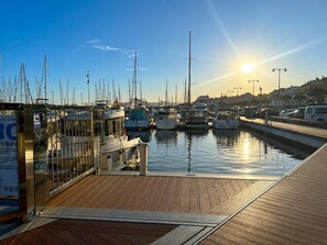 Ein Yachthafen mit vertäuten Booten, ein Holzdeck und ein klarer Himmel.