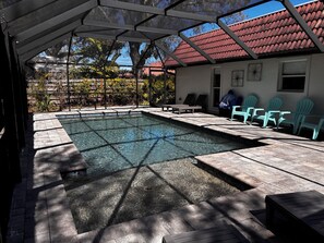 En opvarmet swimmingpool med liggestole og en terrasse.