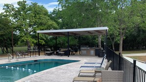 A poolside area with lounge chairs, a covered seating area, and a barbecue grill. - Firefly Cabin, Lake Whitney , Pool & Hot Tub, Boat Parking Fire Pit, Grills. (Clifton)
