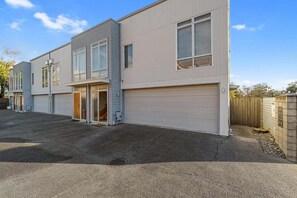 Ein modernes, zweistöckiges Gebäude mit Garage, großen Fenstern und einer flachen Dachfläche.