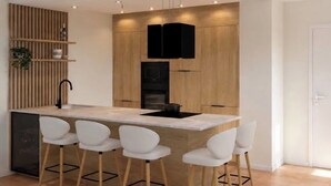 A modern kitchen with a central island, bar stools, wooden cabinetry, and built-in appliances. - LARIMAR APARTMENT (Saint Martin)