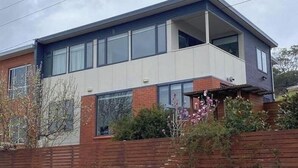 Een modern huis met twee verdiepingen, een balkon, grote ramen en een gevel van baksteen.