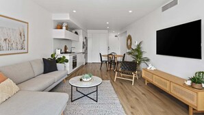 Een moderne woonkamer met een bank, salontafel en een televisie aan de muur.