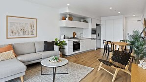 Een moderne woonkamer met een bank, salontafel en een eethoek met stoelen.