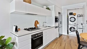 Een moderne keuken met witte kastjes, een inbouwoven, een kookplaat en een spoelbak.