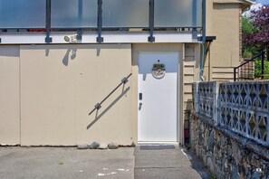 A beige building with a white door, a metal gate, and a small step leading to the door. - Modern and spacious 3-BR basement suite (Vancouver)