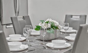 A dining table set with white plates, bowls, and wine glasses, centered with a floral arrangement in a woven basket. - Modern and spacious 3-BR basement suite (Vancouver)