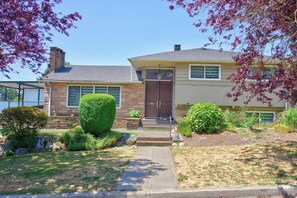 A two-story house with a front porch, a brick chimney, and a well-maintained lawn.
