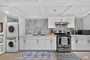 A modern kitchen with built-in appliances, white cabinetry, and marble backsplash. - Modern and spacious 3-BR basement suite (Vancouver)