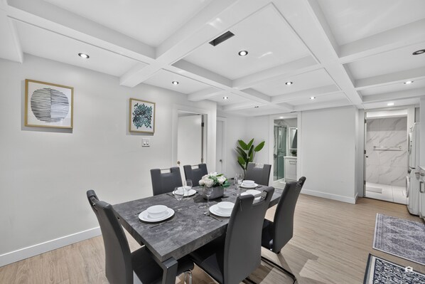 A modern dining area with a rectangular table set for four, surrounded by chairs.