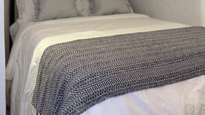 Et soveværelse med seng, hvide gardiner, et vindue og en loftslampe.