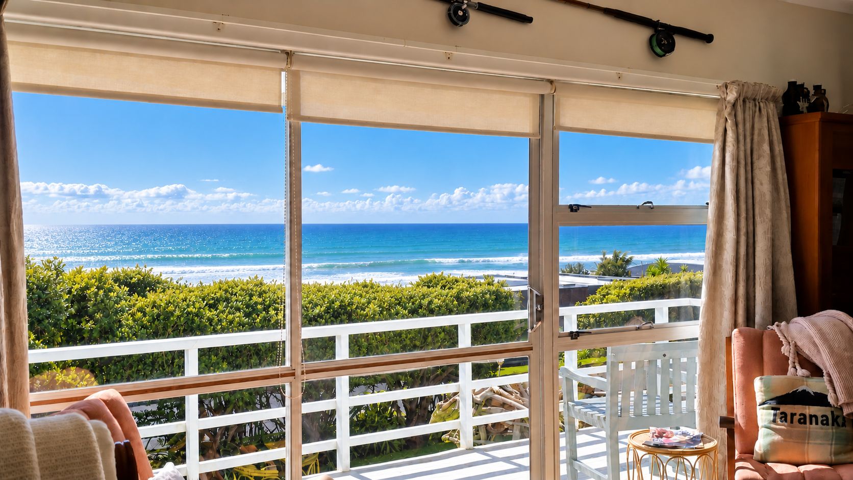 Un balcone con vista sull'oceano, ringhiere bianche e un tavolo con sedie.