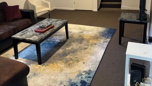 Un salon comprenant un canapé, une table basse, un meuble pour la télévision et un escalier.