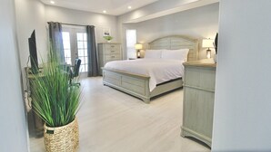 A bedroom with a bed, bedside tables, a dresser, a ceiling fan, and a potted plant. - Blue Pelican Stay - New listing with Hot Tub and Heated Pool (Port St. Lucie)