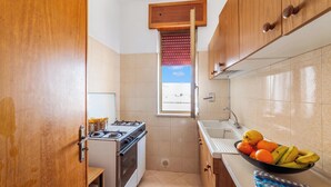 Una cocina compacta con estufa a gas, horno y ventana con persianas.
