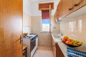 A compact kitchen with a gas stove, oven, and a window with blinds. - Leuca Relax&Sea n.8d, Castrignano del Capo, Italy (Castrignano del Capo)