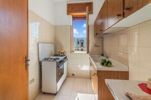Eine kleine Küche mit Gaskochfeld, Spüle und Holzschränken.