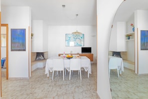 A dining area with a table set for four, a television, and artwork on the walls. - Leuca Relax & Sea n.5d, Castrignano del Capo, Italy (Castrignano del Capo)