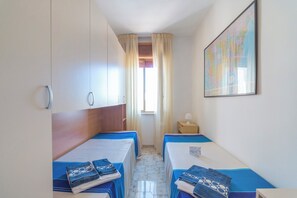 A room with two beds, a map on the wall, a window with curtains, and a small table with a lamp. - Leuca Relax & Sea n.5d, Castrignano del Capo, Italy (Castrignano del Capo)