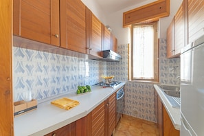 A kitchen with wooden cabinets, a stove, and a window. - Leuca Relax & Sea n.5d, Castrignano del Capo, Italy (Castrignano del Capo)