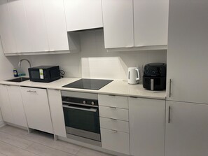 A modern kitchen with white cabinets, a black microwave, a coffee maker, and a dishwasher.