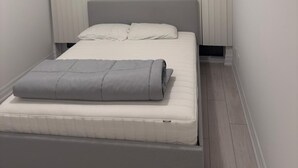 Een moderne slaapkamer met een bed, een plafondlamp en een raam met jaloezieën.