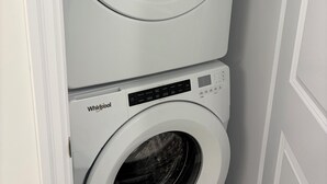 Een Whirlpool wasmachine en droger op elkaar gestapeld in een hoek.