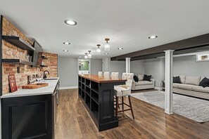 Een moderne keuken met een bar, houten vloeren en een wand van baksteen.