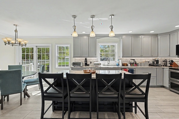 Une cuisine moderne avec des meubles gris, un îlot central et des luminaires suspendus.