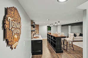 Une cuisine moderne avec un comptoir-bar en bois, des meubles de couleur noire et une enseigne décorative.