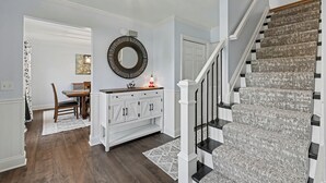 A staircase with a textured carpet, a dining area with a white cabinet and a mirror, and a ceiling light fixture. - Modern Oasis-Pool, Hot-tub, Bar near Saratoga (Ballston Spa)