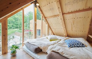 Um quarto com teto de madeira, uma cama com almofadas e um vaso de planta.