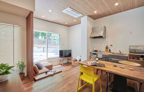 Uma sala de estar moderna com sofá, TV, mesa de jantar e cadeiras amarelas.