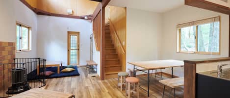 A spacious room with a wooden floor, a staircase, a dining area, and a kitchen with a sink.