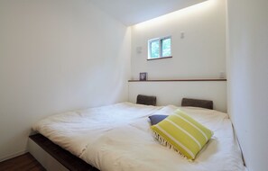 Una cama individual con cabecera, una ventana pequeña y una repisa encima de la cama.