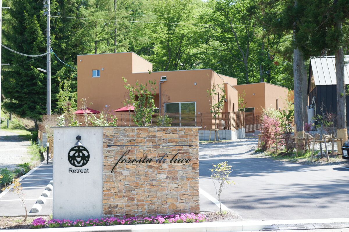 Un refugio con entrada de pared de piedra, zona de estacionamiento y un edificio de diseño moderno.
